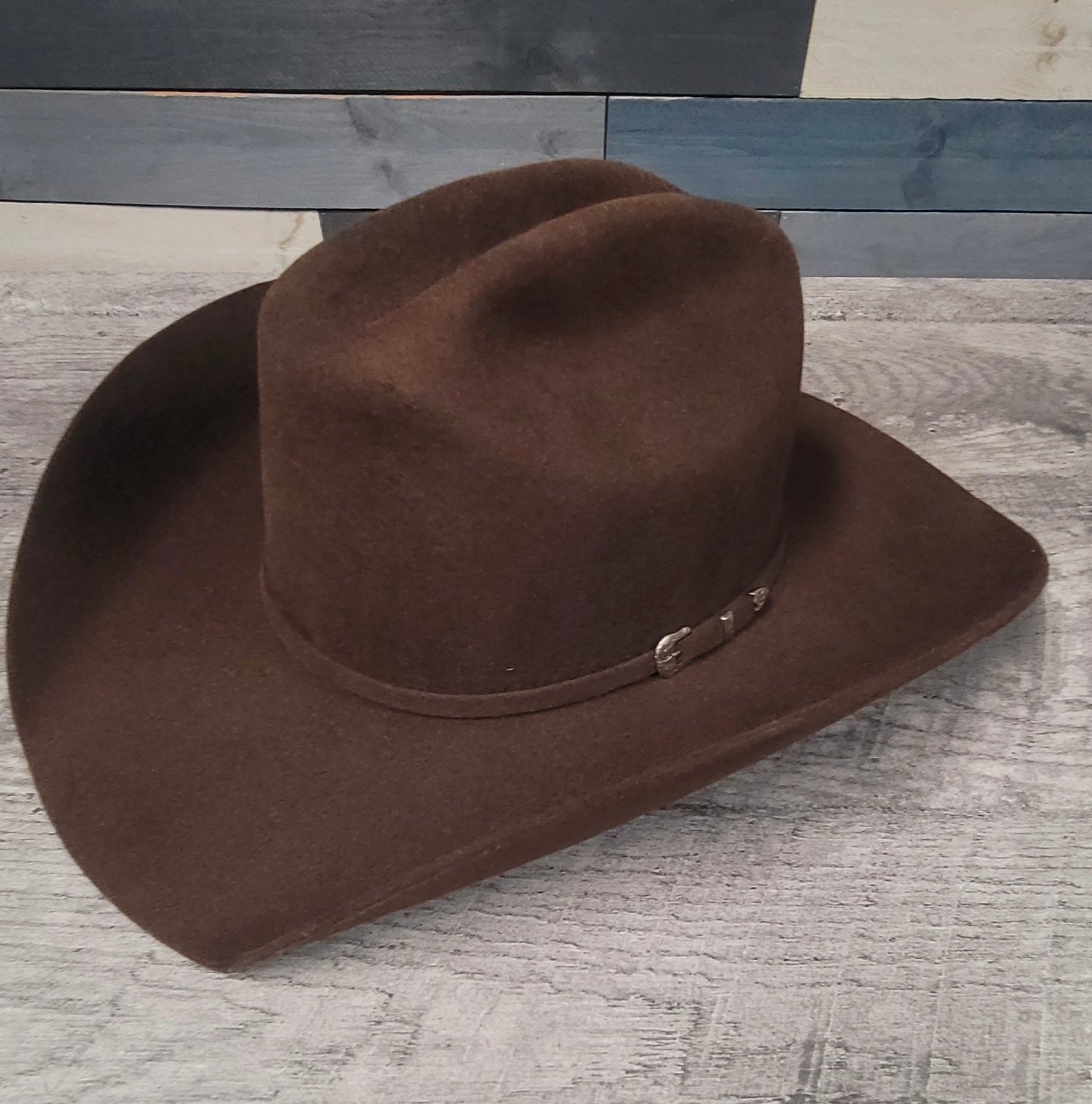 Brown cowboy hat with a belt on a textured surface